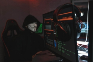 Hacker in dark room with hoodie at the computer hacking on the internet